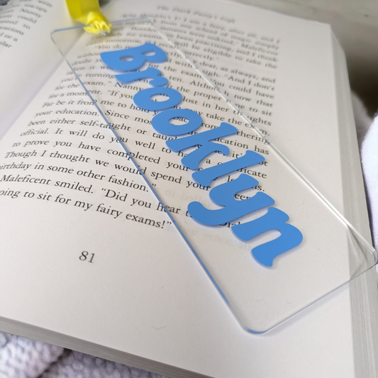 A clear name bookmark rested on an open book. The customised name is in a lovely blue colour.