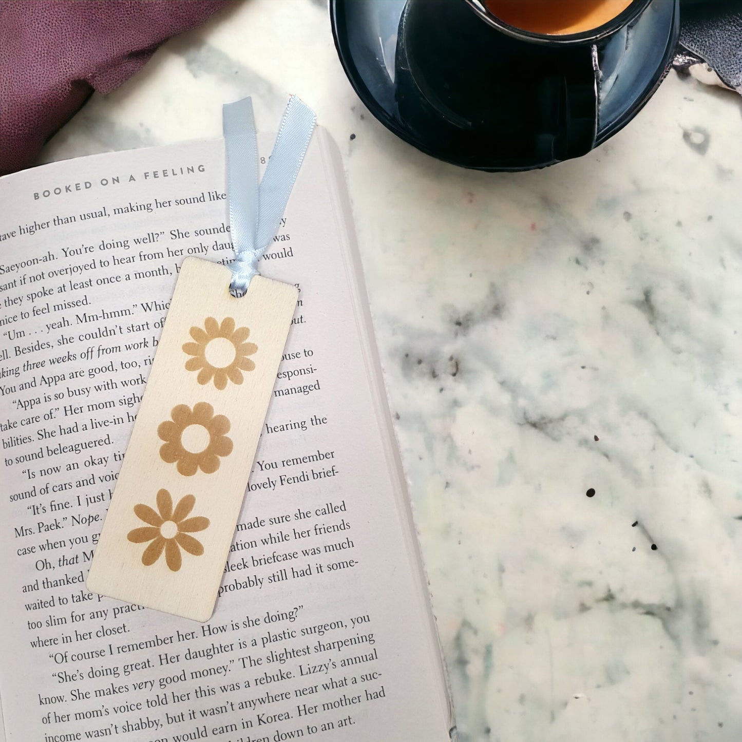 small floral daisy bookmark on an open book. Made with pretty wood and light blue ribbon.