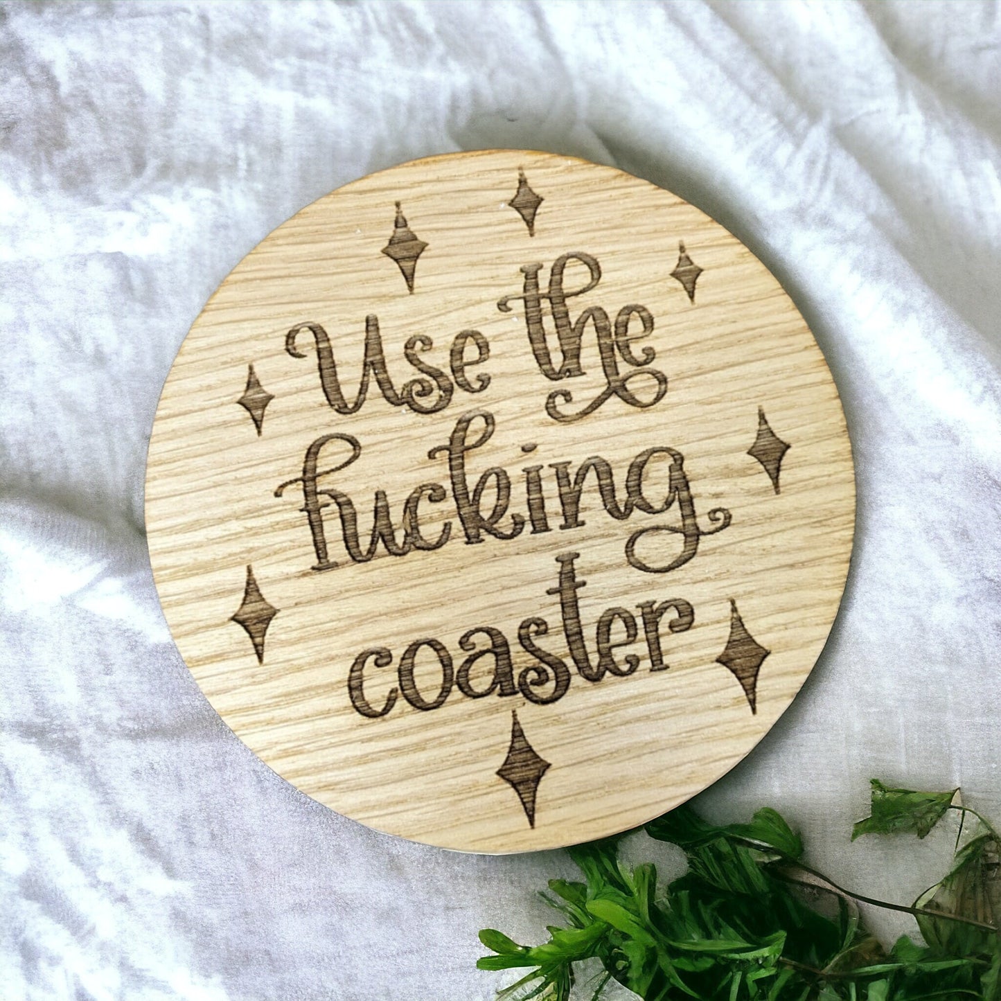 Cosy oak round coaster with the funny saying use the fucking coaster engraved in the middle.