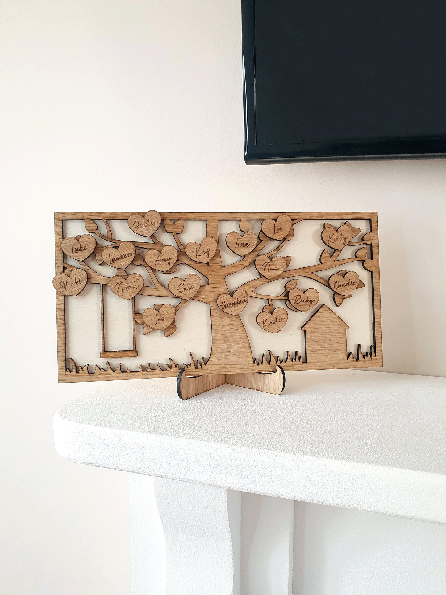 two tone wooden family tree on a fireplace mantel. With 16 different family member hearts engraved from oak.