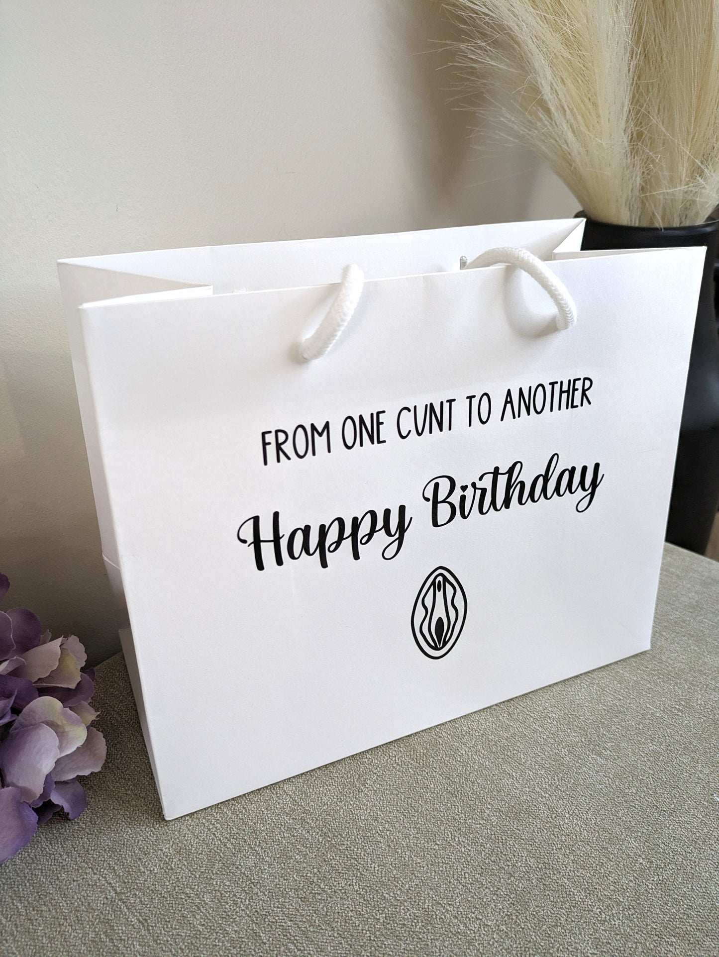 A White gift bag with a line art vagina and the wording from one cunt to another