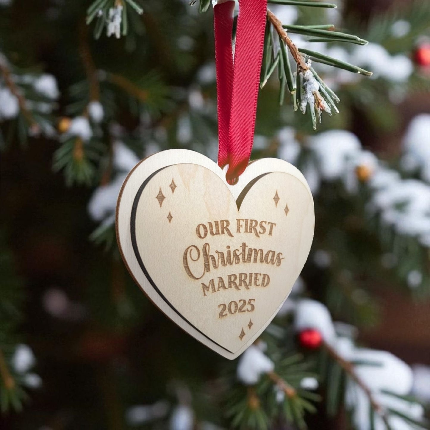 Wooden heart christmas ornament with 'Our First Christmas Married 2025' text on a Christmas tree.