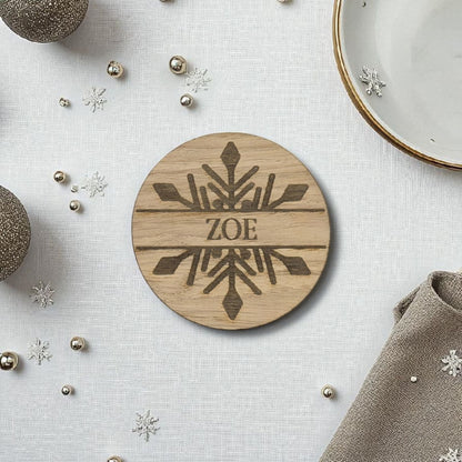 Wooden christmas name place setting with 'ZOE' engraving on a decorative surface with snowflake ornaments.