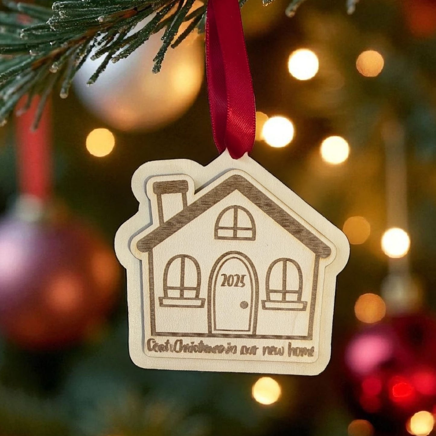 Decorative house ornament with '2025' on a Christmas tree with lights and ornaments.