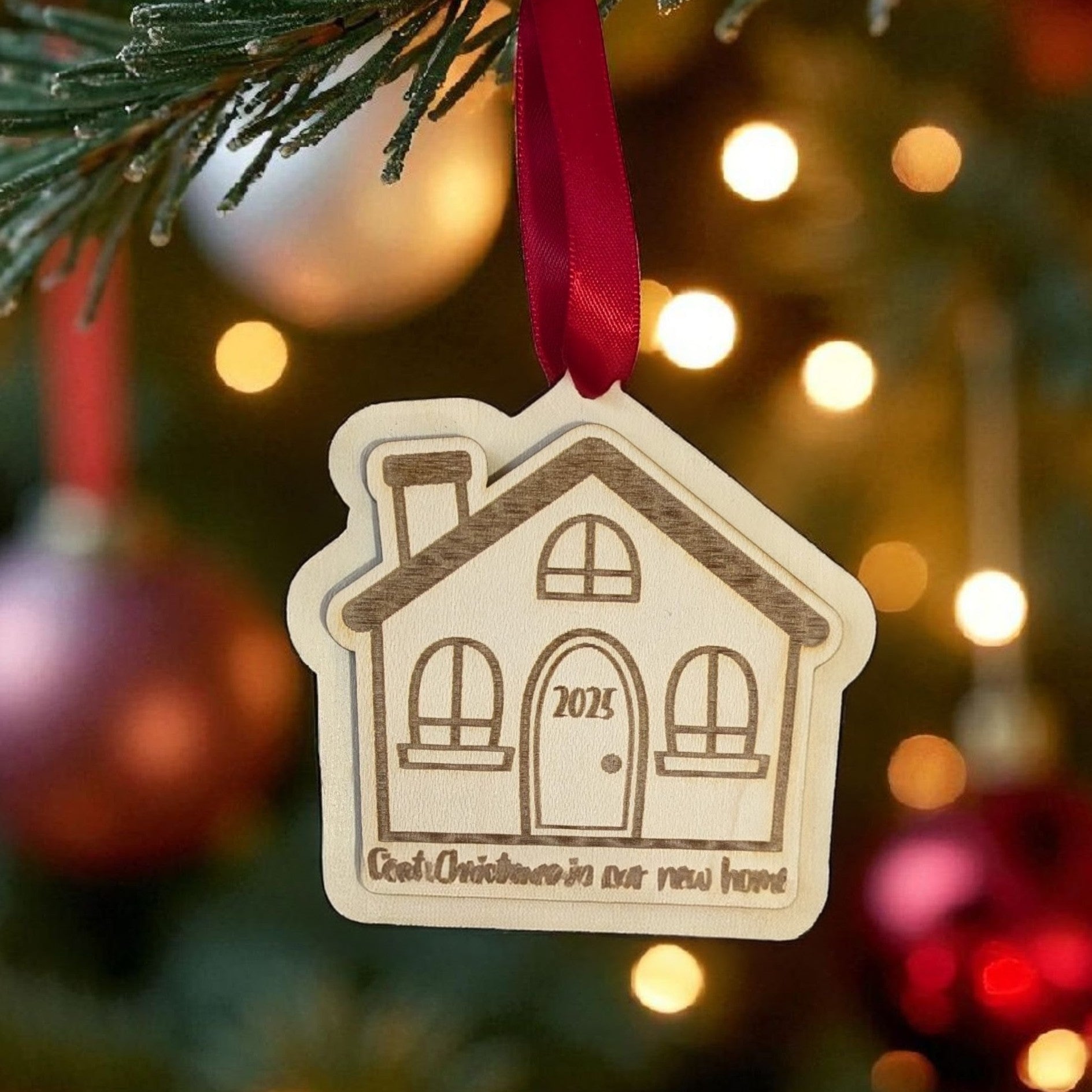 Decorative house ornament with '2025' on a Christmas tree with lights and ornaments.
