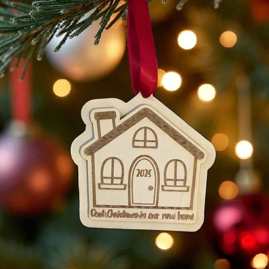 Decorative house ornament with '2025' on a Christmas tree with lights and ornaments.