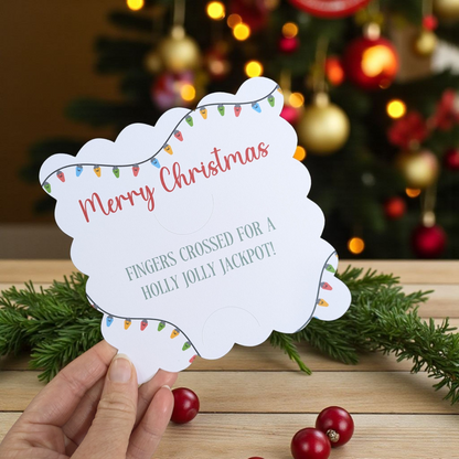 Hand holding a 'Merry Christmas' card with festive lights against a Christmas tree background.