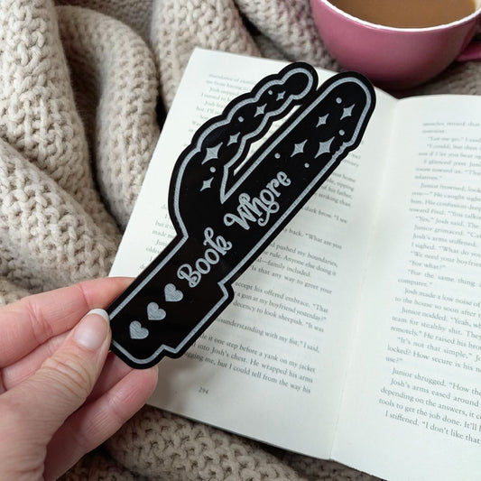 Black bookmark with 'Book Whore'  text held over an open book.