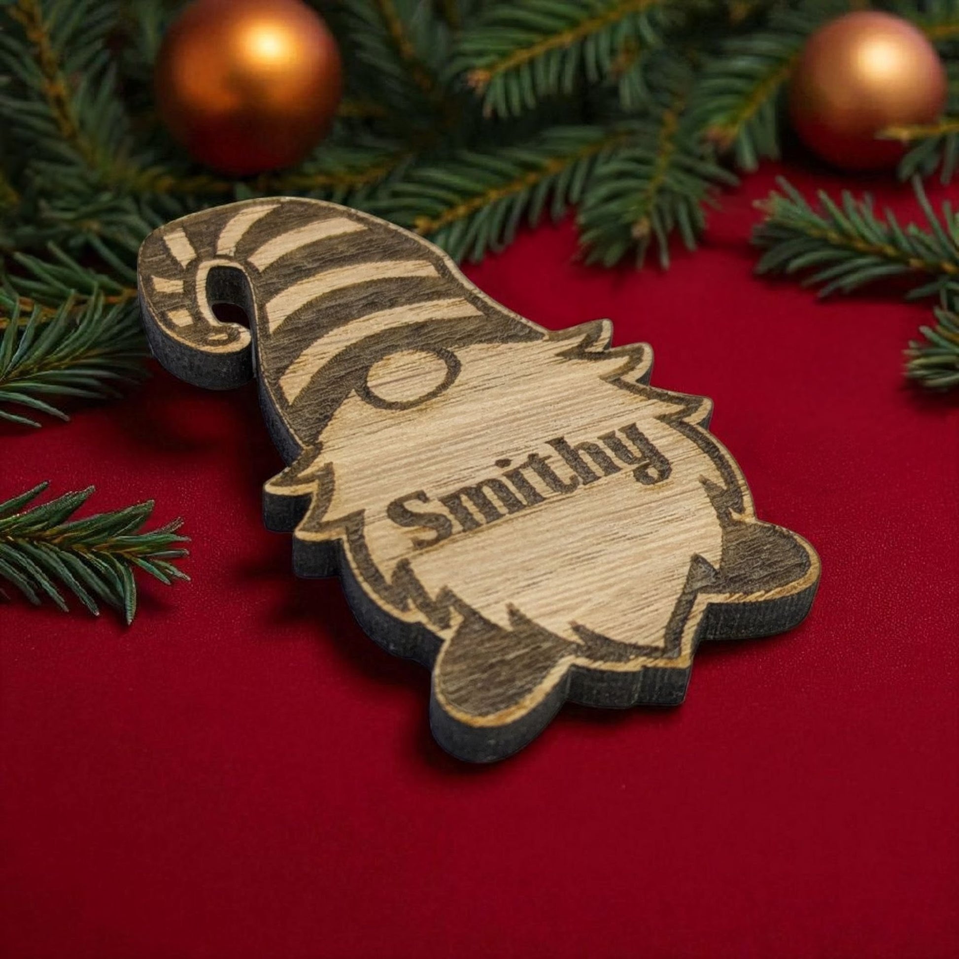Wooden chistmas place card with 'Smithy' engraved on a red background with Christmas decorations.