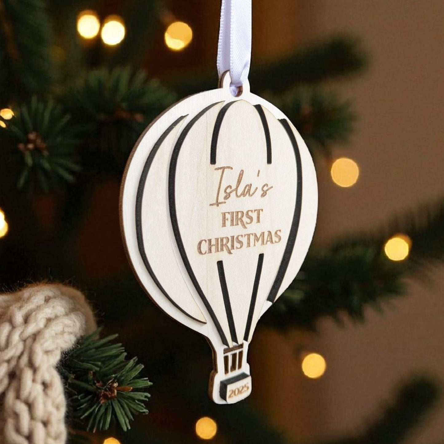 Hot air balloon ornament with 'Isla's First Christmas' text on a Christmas tree.