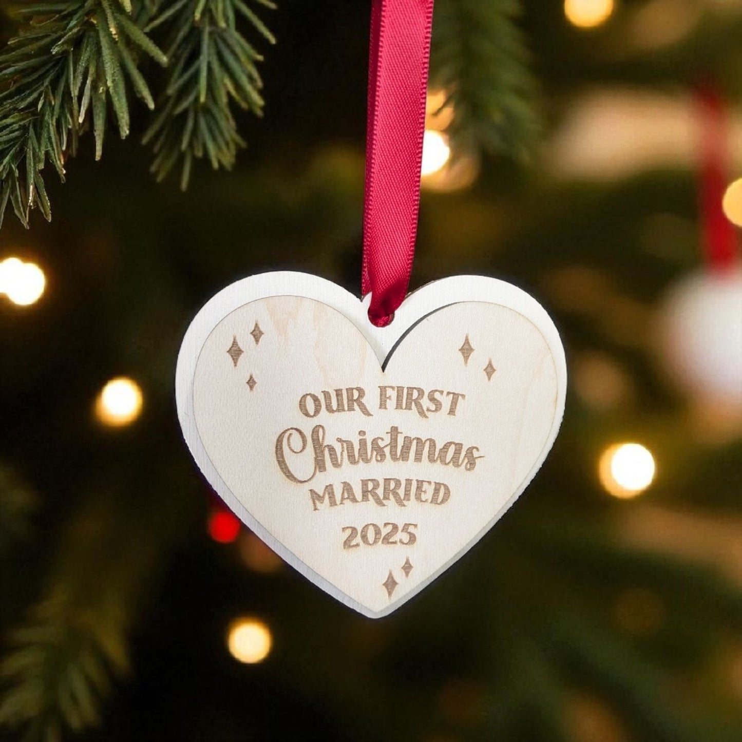 Heart-shaped ornament with 'Our First Christmas Married 2023' text on a Christmas tree.