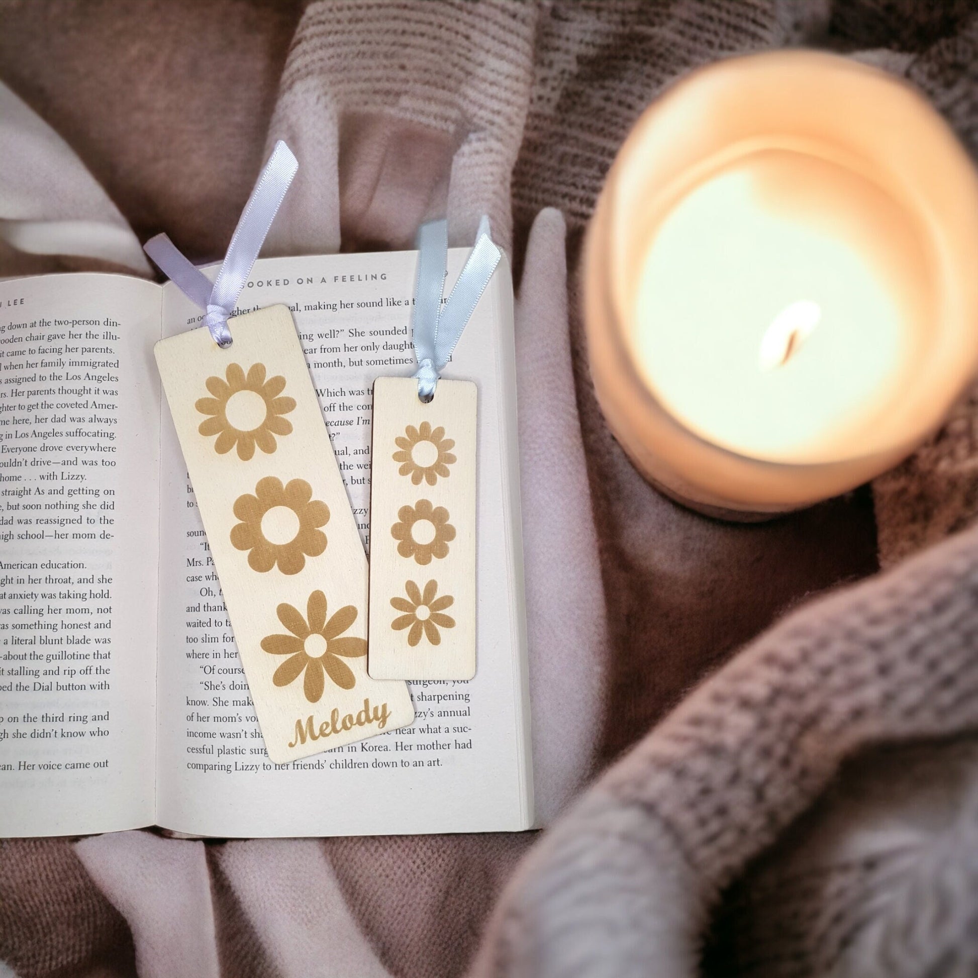 cute daisy design bookmarks on an open book in a cosy room. Bookmarks are made with natural wood.