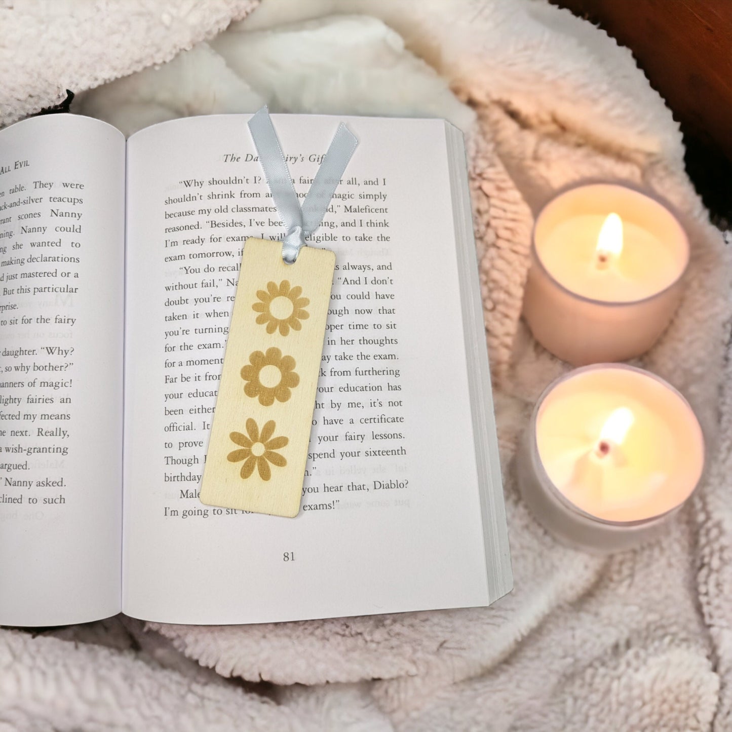 small woden bookmark with ribbon. In the middle it has 3 delicate daisy designs engraved