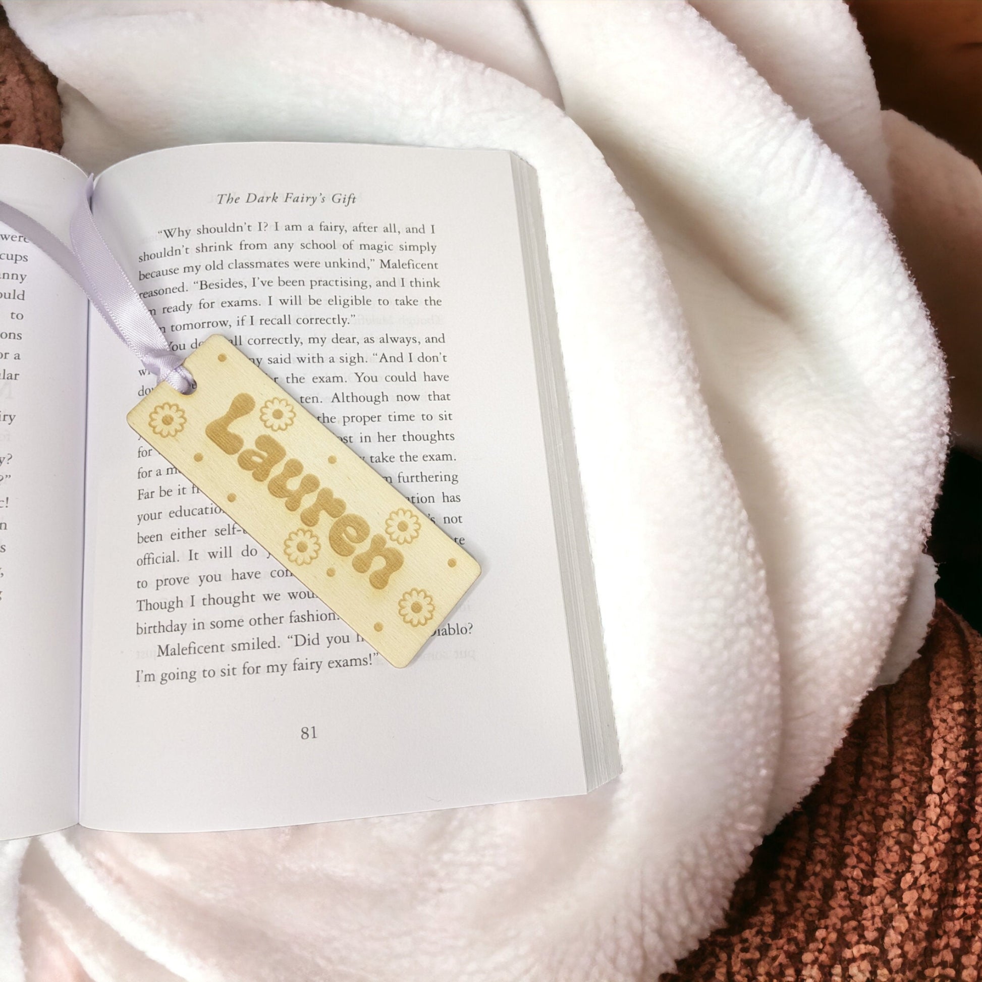 a small personalised daisy bookmark. with polka dots and a name in the middle. Lilac ribbon is attached at the top to keep your page in a book.