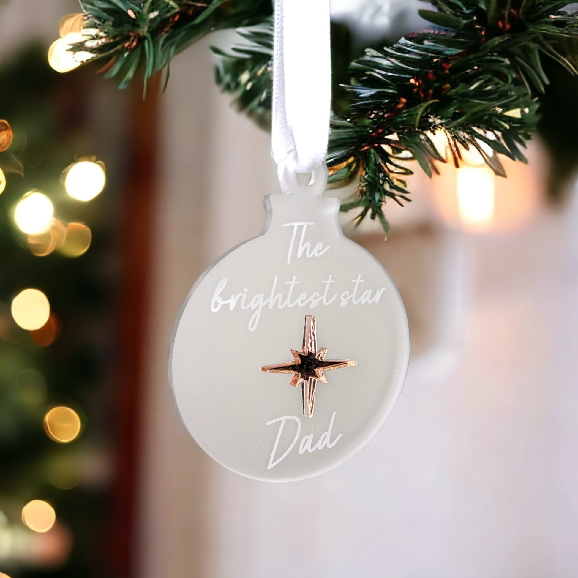 A hanging christmas ornament with a rose gold star. Reading the brightest star dad
