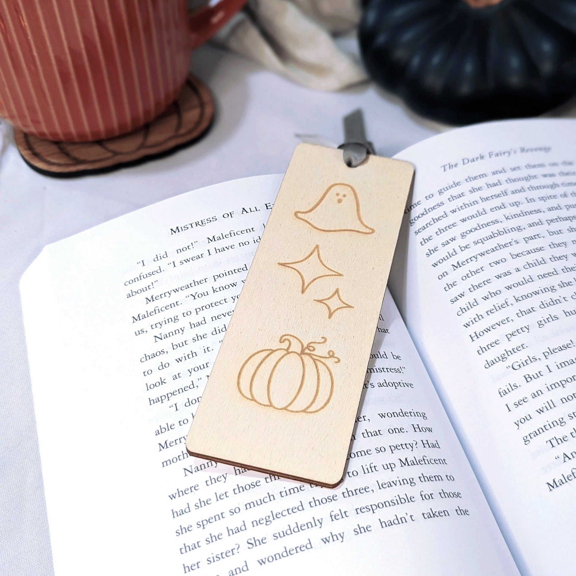 A wooden bookmark with engraved stars, pumpkin and ghost. 