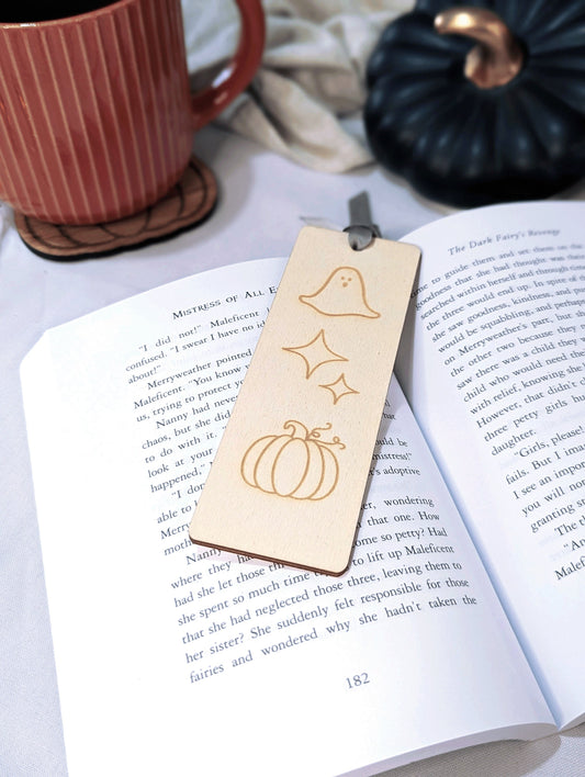 A wooden bookmark with engraved stars, pumpkin and ghost. 